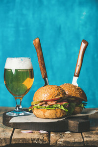 Beef burgers with crispy bacon vegetables and glass of beer