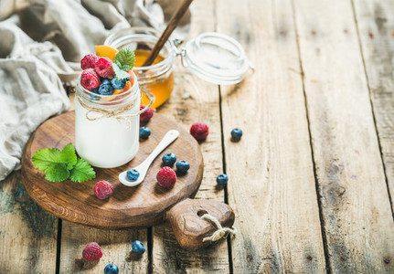 Glass jar of yogurt with berries  mint and honey