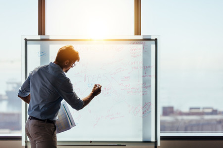 Entrepreneur putting his business ideas on whiteboard in boardro