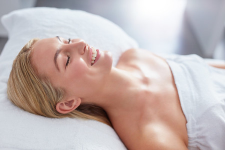 Smiling woman in a day spa relaxing on massage table