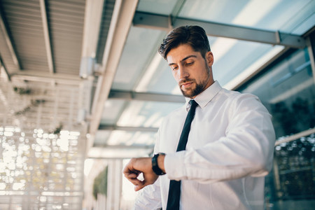 Business executive checking time outside airport