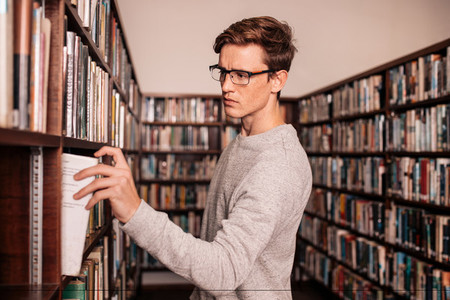 University student taking a book from shelf in library