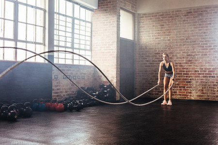 Athlete exercising in gymnasium using training ropes