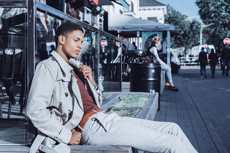 Stylish young African American man posing in a street cafe