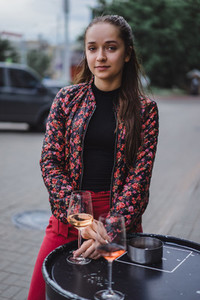 Stylish young girl drinks wine in a street cafe on a summer terr