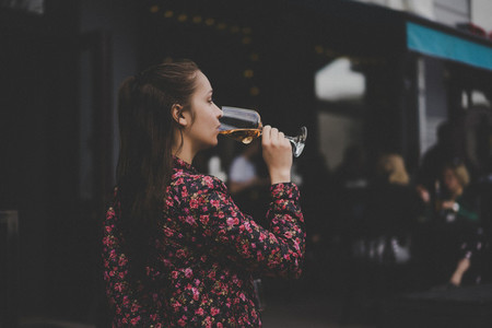 Stylish young girl drinks wine in a street cafe on a summer terr