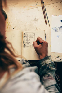 Woman artist sketching on book