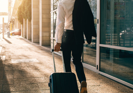Businessman walking outside airport with suitcase