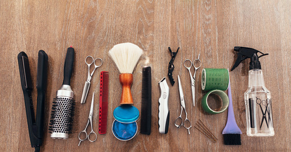 Hairdressing accessories arranged on wooden background
