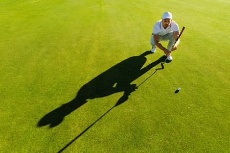 Golf player aiming shot with club on course