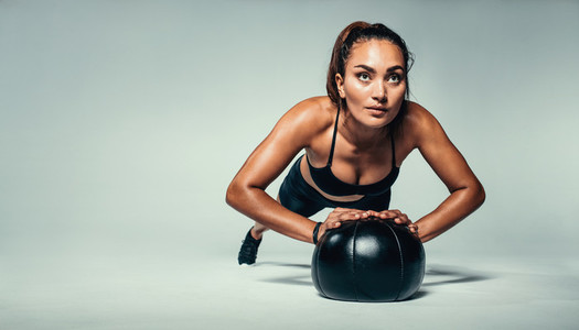 Fit woman doing push up on medicine ball