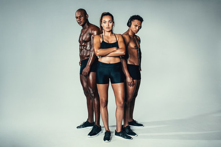 Group of muscular people standing on grey background