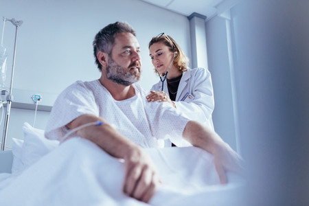 Hospitalised man getting examined by female physician