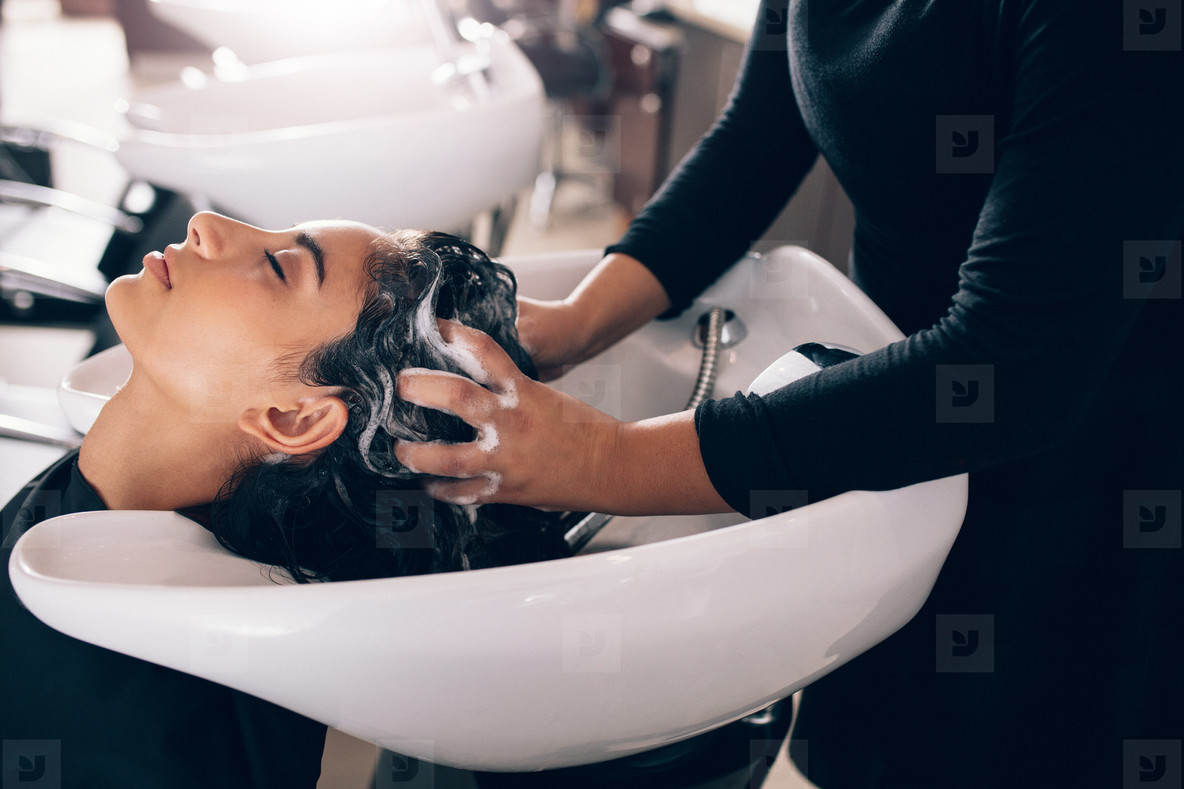 Woman getting hair shampooed at salon