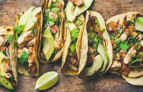 Tacos with grilled chicken avocado fresh salsa sauce and limes