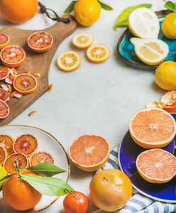 Natural fresh citrus fruits in ceramic plates over grey background
