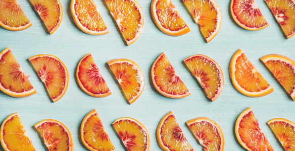 Fresh juicy blood orange slices over blue background  wide format