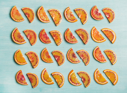 Fresh juicy blood orange slices placed in rows blue background