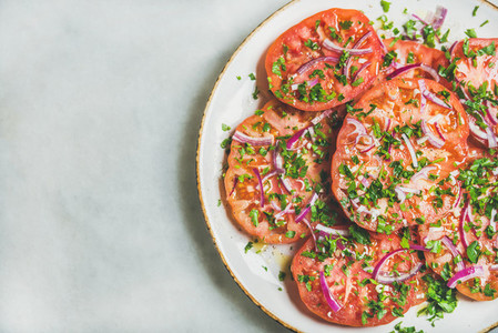 Fresh heirloom tomato  parsley and onion salad in white plate