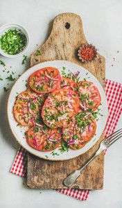 Fresh tomato parsley and onion salad on shabby wooden board