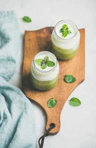 Ombre layered green smoothies in glass jars on wooden board