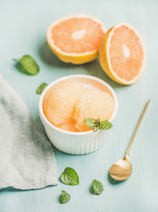 Pink grapefruit sorbet with fresh mint in white bowl