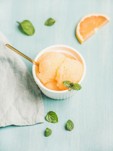 Pink grapefruit sorbet with fresh mint leaves in white bowl