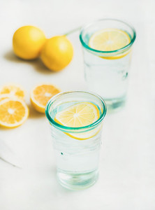 Detox lemon water in glasses served with fresh lemons
