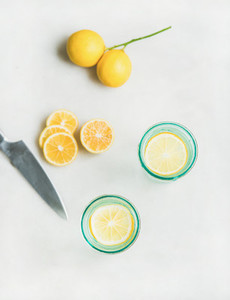 Detox lemon water in glasses and fresh lemons  top view