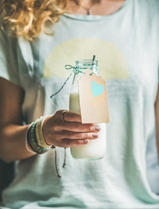 Young blond woman holding bottle of dairy free almond milk