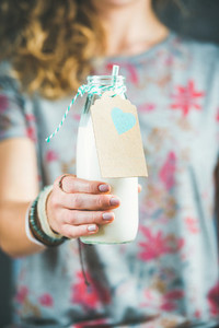 Young woman in t shirt holding bottle of dairy free almond milk