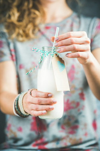 Young woman holding bottle of dairy free almond milk