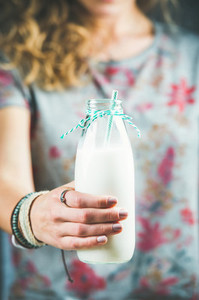 Young woman holding bottle of dairy free almond milk with straw