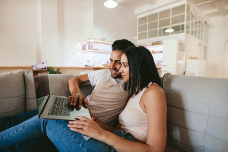 Young couple relaxing on couch with laptop