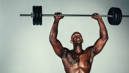 Muscular african man exercising with barbell
