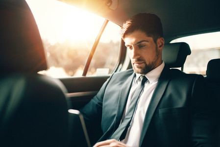 Businessman working inside the car while travelling
