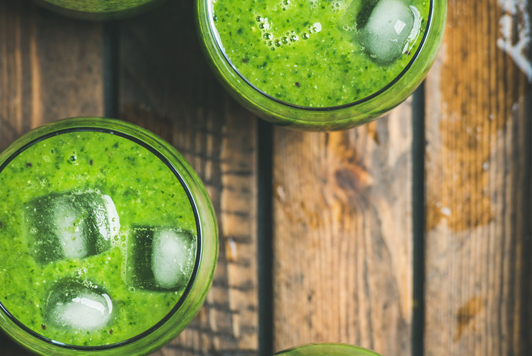 Fresh green smoothie with ice cubes in rustic wooden tray