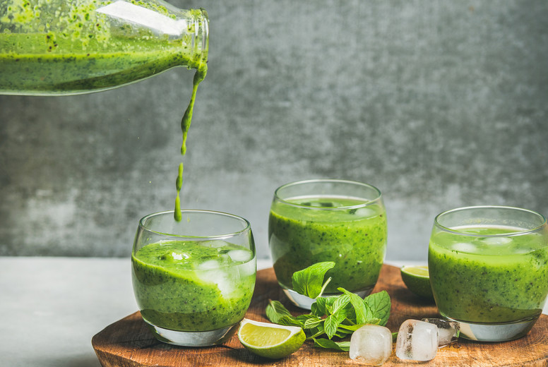 Fresh smoothie pouring from bottle with ice, mint and lime