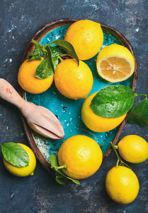 Freshly picked lemons with leaves in bright blue ceramic plate