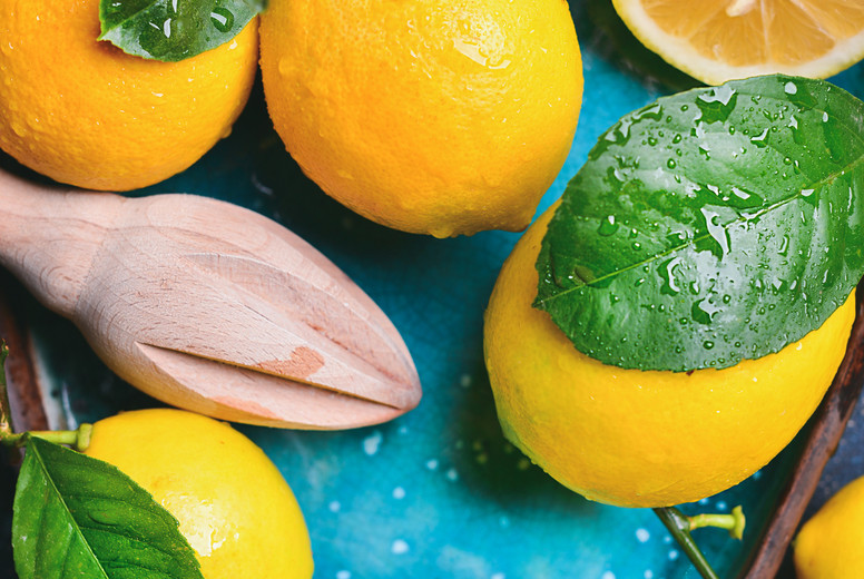 Close-up of freshly picked lemons with leaves in blue plate