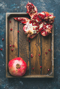 Fresh ripe pomegranates cut in pieces in wooden tray