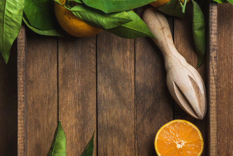Fresh oranges with leaves in dark wooden tray over rustic background, copy space
