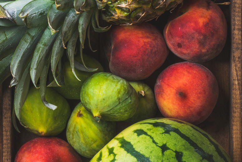 Summer friut variety in wooden tray over dark rustic background