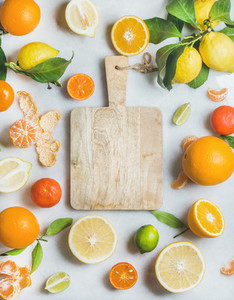 Variety of fresh citrus fruit and wooden board in center