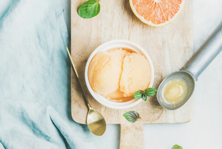 Pink grapefruit sorbet with fresh mint leaves on wooden board