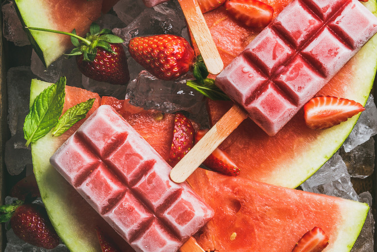 Homemade watermelon strawberry popsicles on ice with fresh fruits
