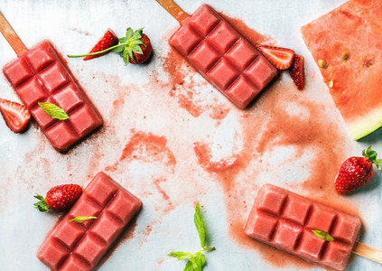 Strawberry watermelon ice cream popsicles with fresh mint leaves over steel tray background  copy space