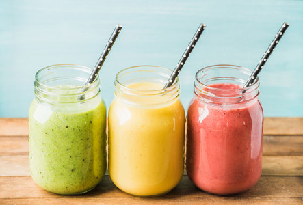Three jars of fresh fruit smoothies with various colors and tastes  Green  yellow  red