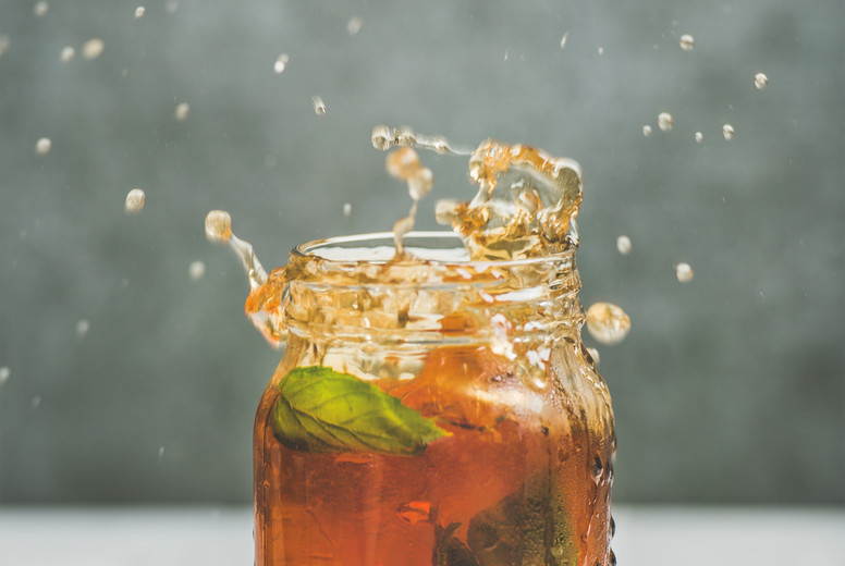 Iced tea with bergamot, lemon, mint in jar with splashes