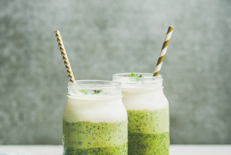 Ombre layered green smoothies with mint in jars with straws